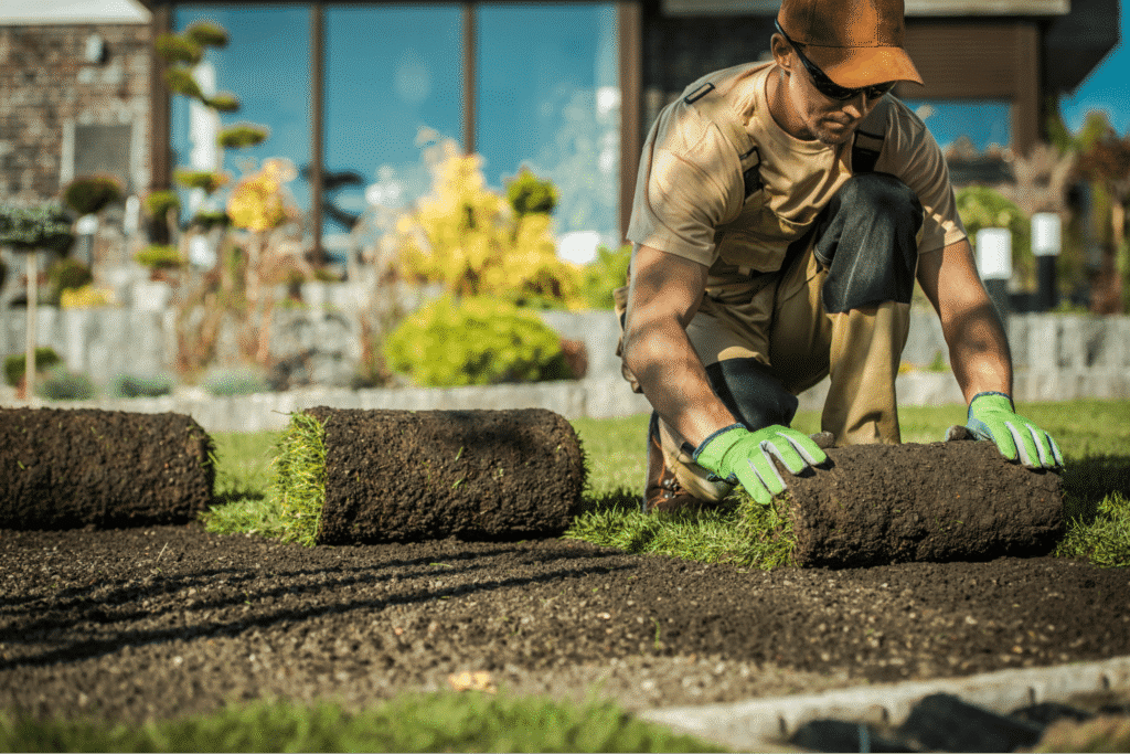 Lawn installation tips: a gardener laying sod for a lush green lawn.